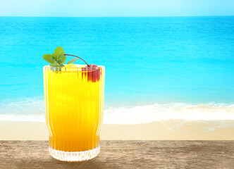 Tasty pineapple cocktail in glass on wooden table against seascape. Space for text