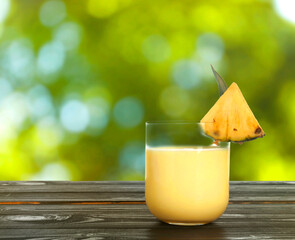 Tasty pineapple cocktail in glass on wooden table outdoors. Space for text