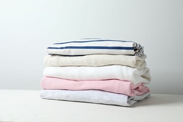 A stack of freshly washed, neatly folded clothing on a wooden table