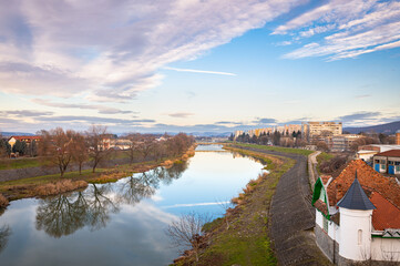 Fototapeta premium Beautiful view of the calm waters of the Mures River in the city of Târgu Mureș (Hungarian: Marosvásárhely) in Transylvania, Romania.