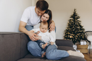 Family enjoying christmas time together on sofa with christmas tree