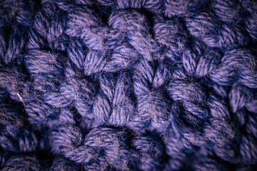 A macro view of dark blue knitted fabric showcasing the rich texture and thick yarn weave. The soft and intricate fibers highlight the cozy and durable material.