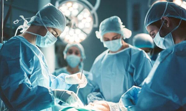 Group of surgeons doctors and nurses performing an operation in a bright modern operating room