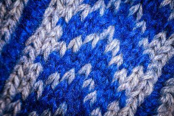 A detailed macro shot of blue and white knitted fabric, showcasing the soft texture and intricate weave of the yarn. The color contrast highlights the artistic pattern.