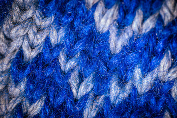 A detailed macro shot of blue and white knitted fabric, showcasing the soft texture and intricate weave of the yarn. The color contrast highlights the artistic pattern.
