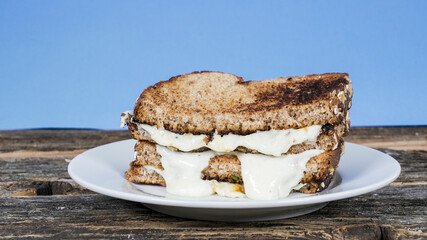 Delicious grilled cheese sandwich on plate with nlue background and rustic table