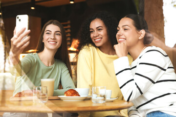 Women taking selfie at coffee meeting in cafe, view through window