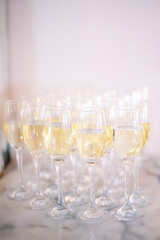Champagne glasses stand on a table with a white tablecloth, wedding reception, alcohol at the party.