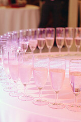 Champagne glasses stand on a table with a white tablecloth, wedding reception, alcohol at the party.