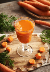 A glass of fresh carrot juice on a wooden table