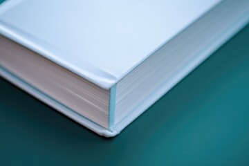 A single white book resting on top of a green table, suitable for use in educational or decorative...