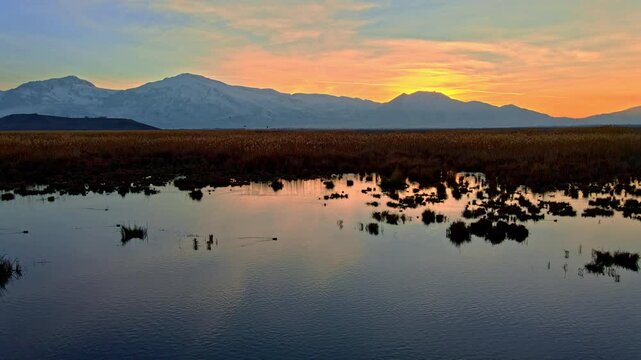 Aerial view video of a mountain range at sunrise, with golden light illuminating the peaks and valleys. Perfect for nature, adventure, and landscape-themed projects.