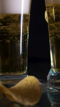 chips beer pouring beer into stein glass with American football, snack food, and bottles of beer, against a black background with lens flare.