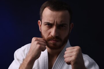 Karate fighter in uniform on dark background