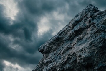 Fototapeta premium A rugged rock face with a cloudy sky in the background, suitable for outdoor or nature-inspired designs