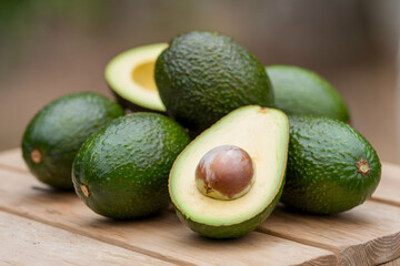 Avocados on wooden surface, one sliced to reveal seed, highlighting freshness