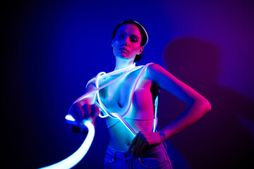 Young model in neon glow posing against a dark blue backdrop