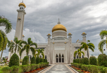 Entrance with palms and green decorated plants to Omar Ali Saifuddien Mosque with golden domes minarets Bandar Seri Begawan, Borneo, Sultanate Brunei Darussalam
