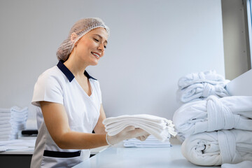 Female dry cleaning worker folding clean laundry and preparing for delivery.