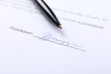Signature and pen on paperwork, closeup view