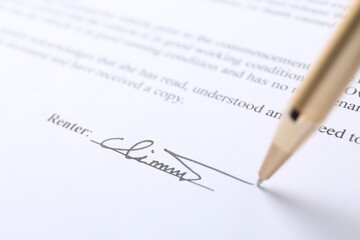 Pen leaving signature on contract, closeup view