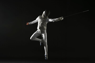 Fencer with epee practicing on black background