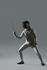 Fencer with epee practicing on gray background