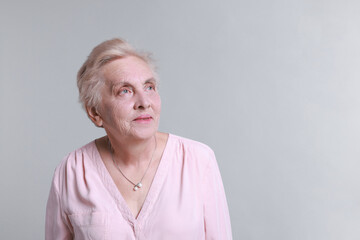 Portrait of senior woman on light background. Space for text