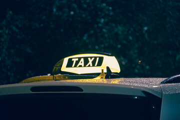 A vibrant and glowing taxi sign lights up on a rainy night, perfectly capturing the essence of...