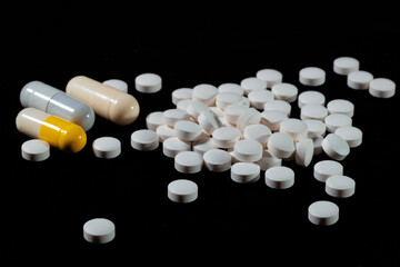 White round tablets are scattered on a black background.