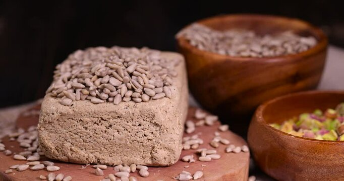 halva from roasted sunflower seeds and crushed into one solid mass, wooden bowl, a sweet delicious dessert made from fried sunflower seeds