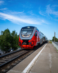 the approaching train to the pyrone against a background of blue sky, trees and cityscape.