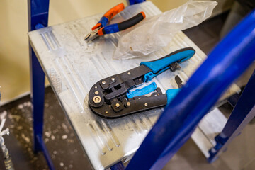 wire crimping tool rests on an aluminum stepladder