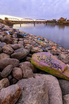 A rock with the word smacker written on it is sitting on a pile of rocks by a bo