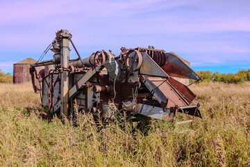 An old, rusted combine harvester sits in a field
