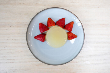 A plate of yuzu jelly with strawberries.