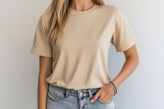 Woman is wearing a tan shirt and blue jeans