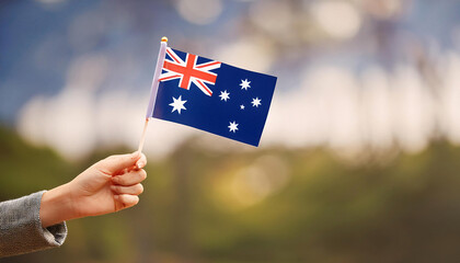 A hand holds a small Australian flag against a blurred outdoor background, showcasing national pride and symbolism Generative AI