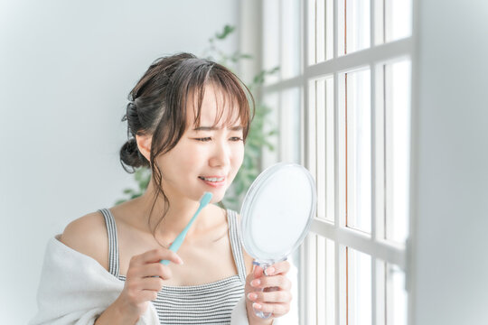 虫歯がしみる・痛い、歯磨きをするアジア人女性の横顔
