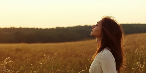 In this serene scene, a woman's silhouette gazes upward in a golden field, symbolizing hope and freedom, evoking feelings of tranquility and connection with nature.