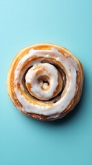 Fototapeta premium Overhead View of Icing-Covered Cinnamon Roll on Blue Background