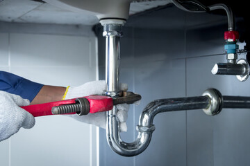 Plumber hands holding wrench doing repairing work at the sink and clogged pipe in bathroom carefully