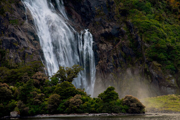 Tall cascading waterfall surrounded by lush green forest and rocky cliffs