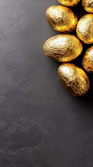 Obraz premium Chocolate eggs wrapped in metallic foil beautifully arranged on a dark textured surface