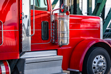 Bright red big rig bonnet semi truck with extended cab and chrome accessories running on the road...