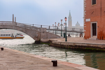 Beautiful marble bridge over a canal with historical architecture in the background, Venice, Italy