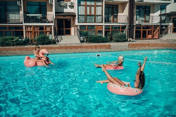 Naklejka premium A group of people are in a pool with pink and white floats. Scene is fun and lighthearted.