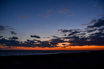 海に沈む美しい真っ赤な夕日と三日月