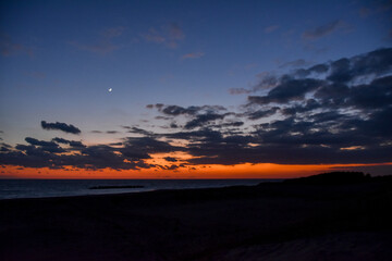 Obraz premium 海に沈む美しい真っ赤な夕日と三日月