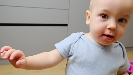 Happy exited baby boy learning to walk at home, smiling on camera. Cute little toddler taking his first steps without any help. Baby first steps and childhood concept